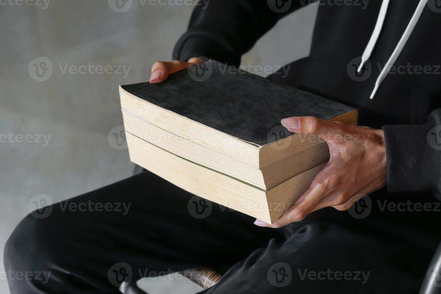 Male hand holding a stack of books. Education and knowledge concept. Portrait of young man book lover photo