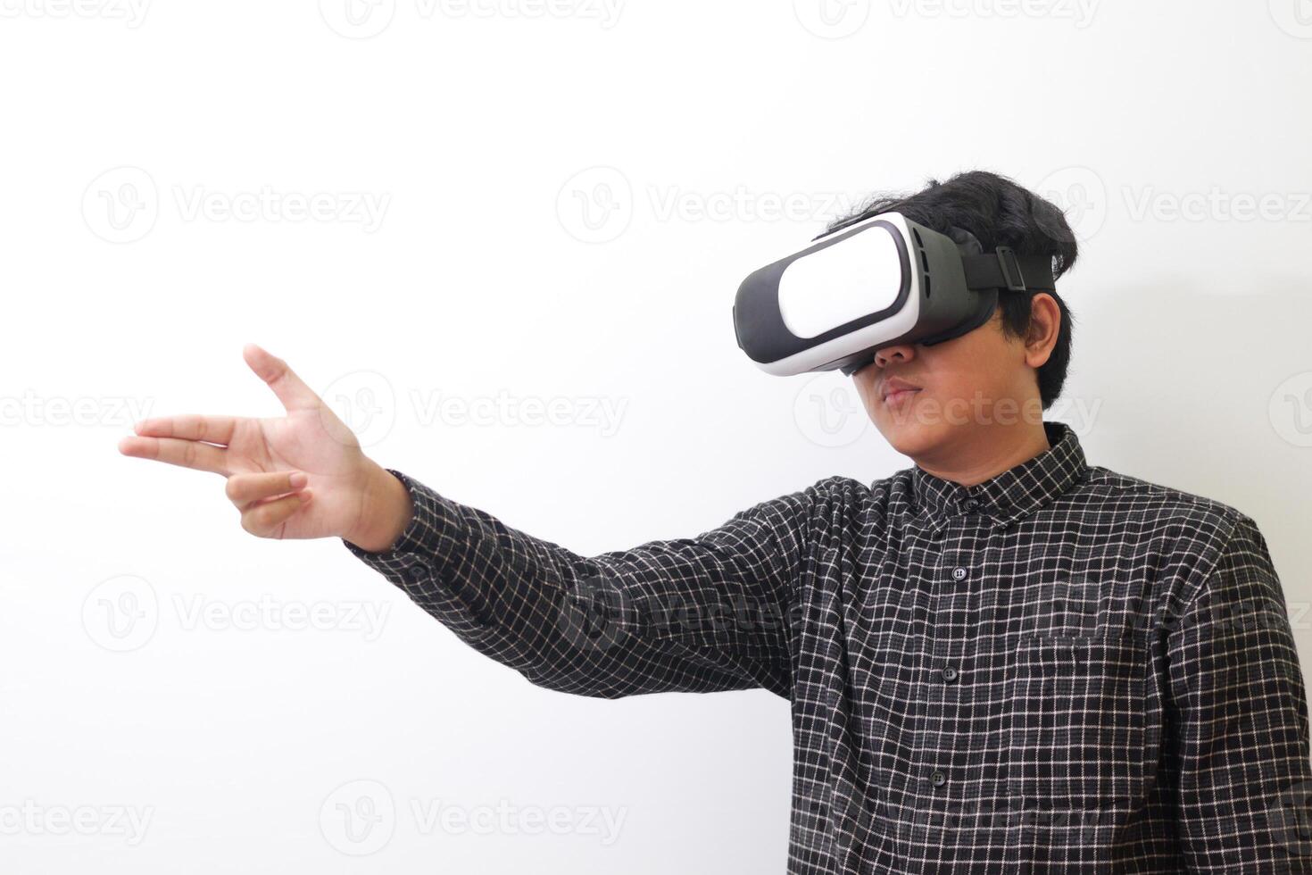 Portrait of Asian man in black plaid shirt using Virtual Reality VR glasses and greet his friend inside the game with opened palm. Isolated image on white background photo