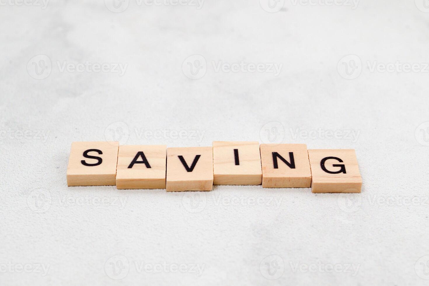 Top view of Saving word on wooden cube letter block on white background. Business concept photo