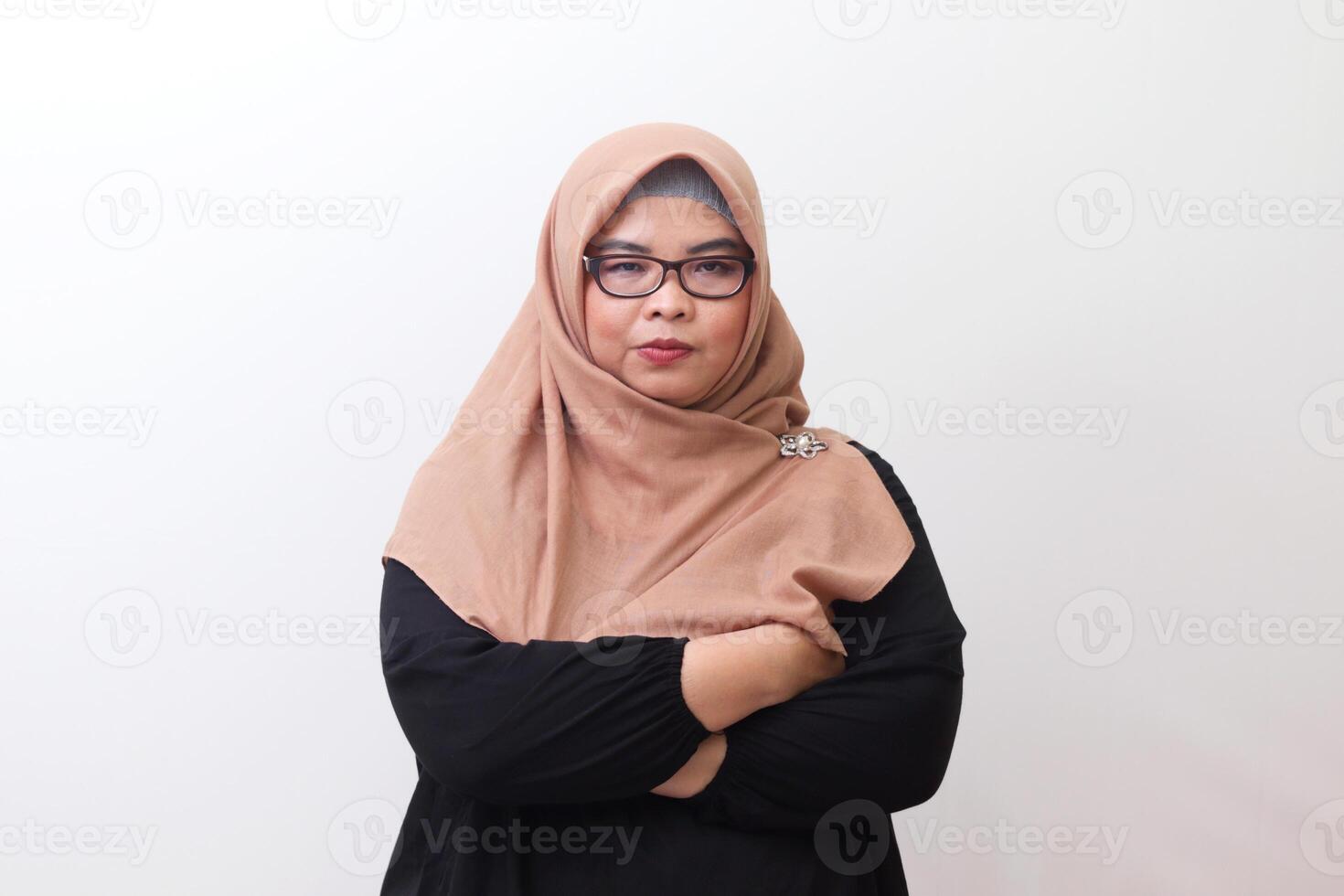 Portrait of annoyed Asian woman with hijab keeping arms crossed and looking at camera with skeptical and distrustful look. Isolated image on white background photo
