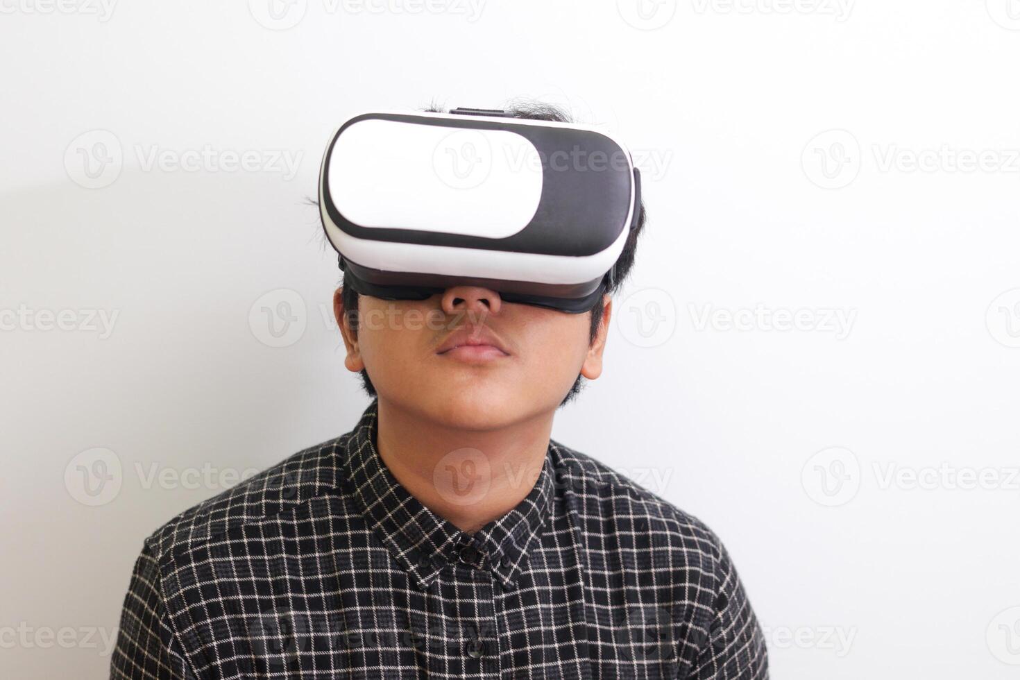 Portrait of Asian man in black plaid shirt using Virtual Reality VR glasses and looking up. Isolated image on white background photo