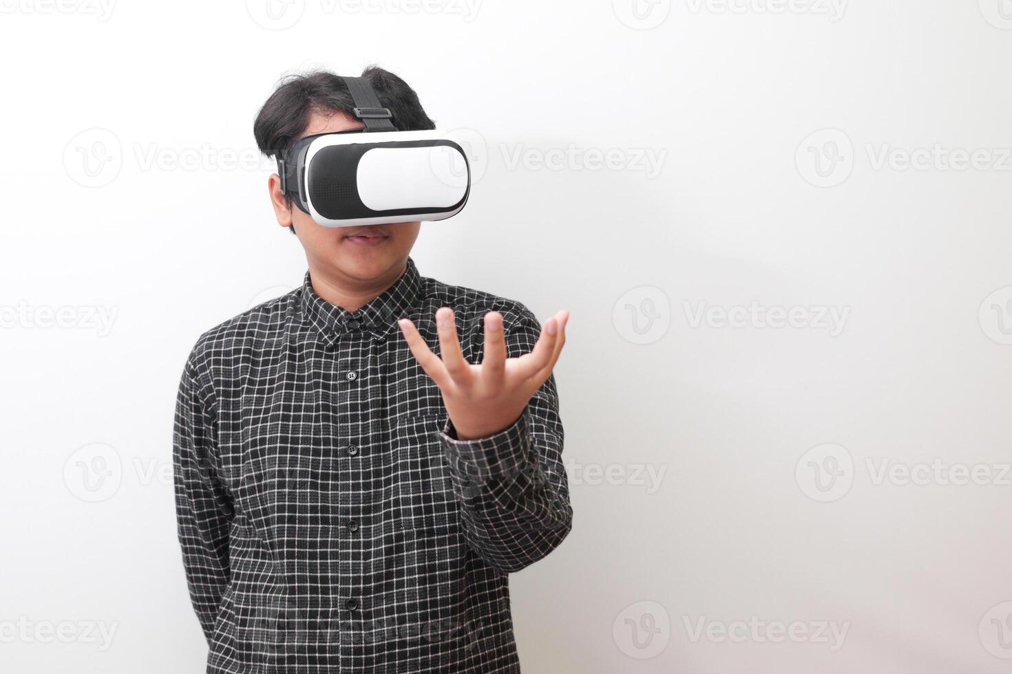 Portrait of Asian man in black plaid shirt using Virtual Reality VR glasses and trying to hold something in front of him. Isolated image on white background photo