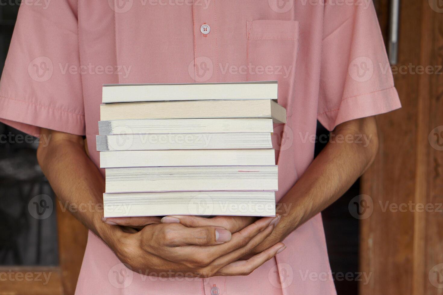 Male hand holding a stack of books. Education and knowledge concept. Portrait of young man book lover photo