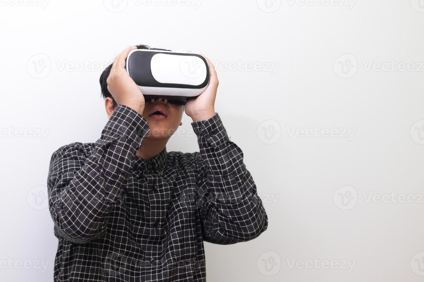 Portrait of Asian man in black plaid shirt using Virtual Reality VR glasses and looking up. Isolated image on white background photo