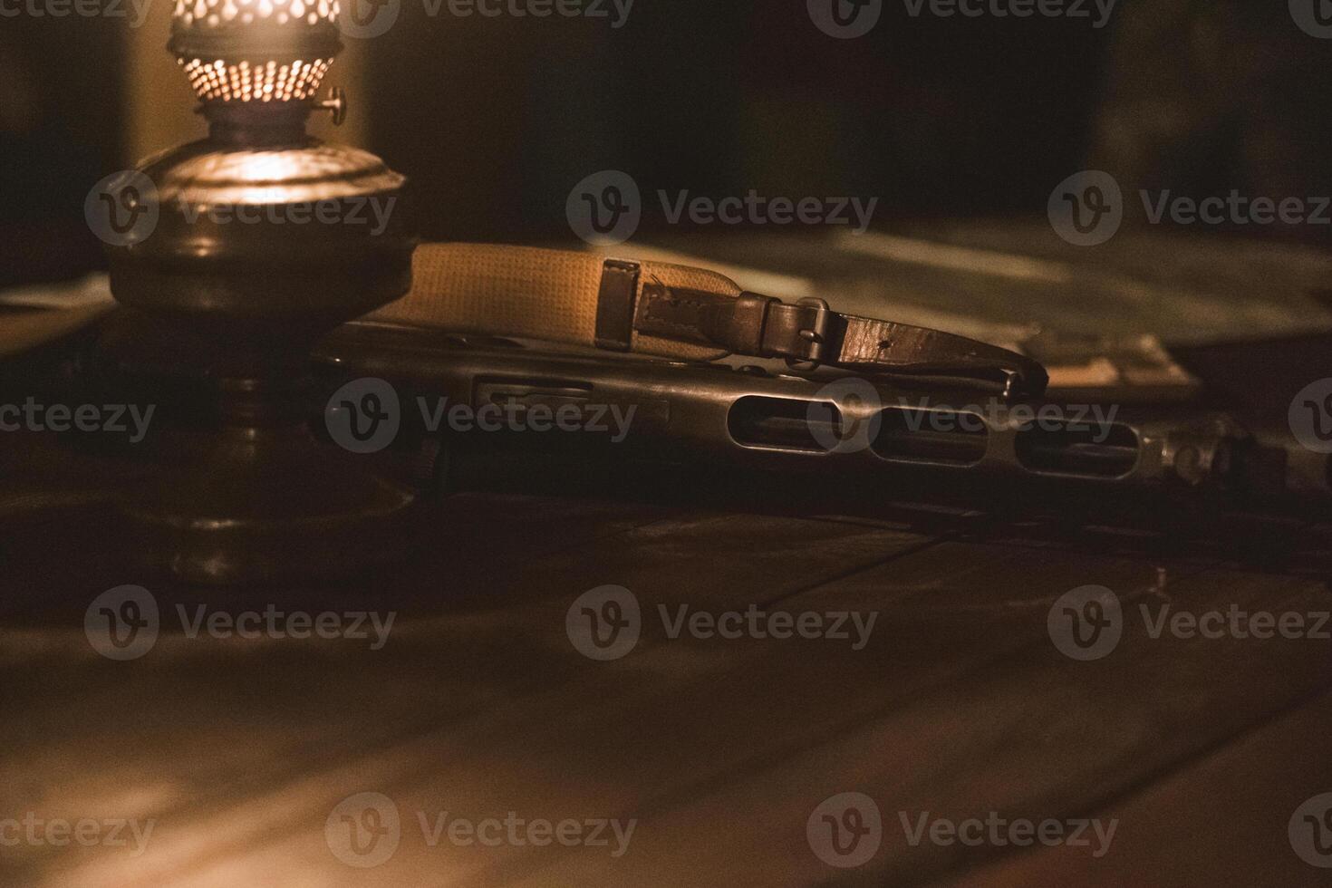 An old Soviet rifle lies on a table next to a kerosene lamp in the semi-darkness photo