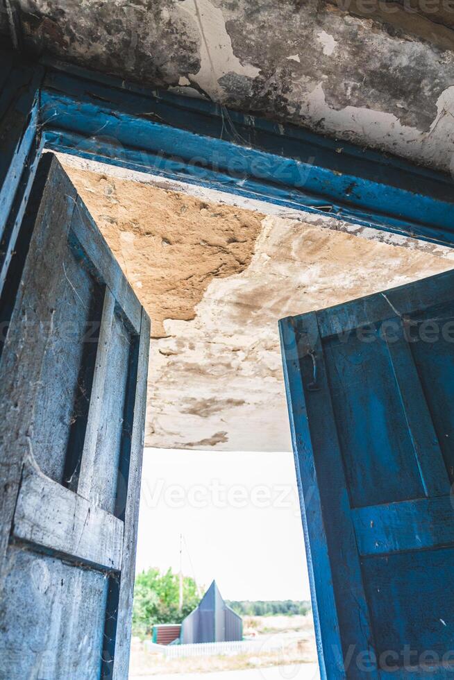 The open, blue doors of the main entrance, to an abandoned, rustic store photo