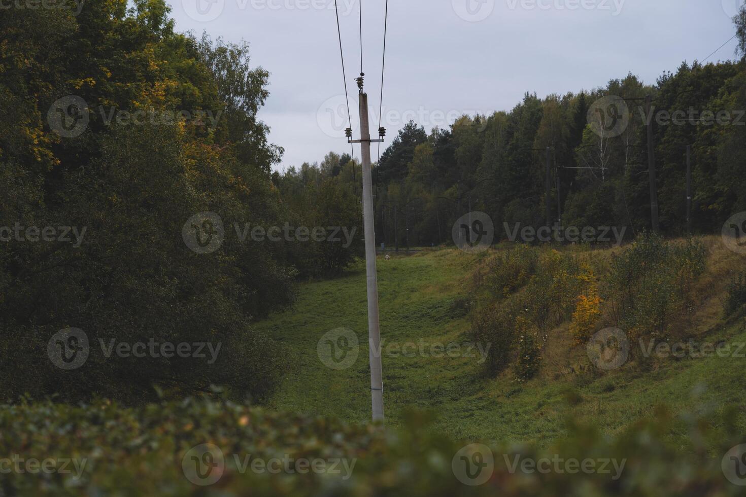 The inclined support of the power line in the autumn, evening field. Cloudy sky photo