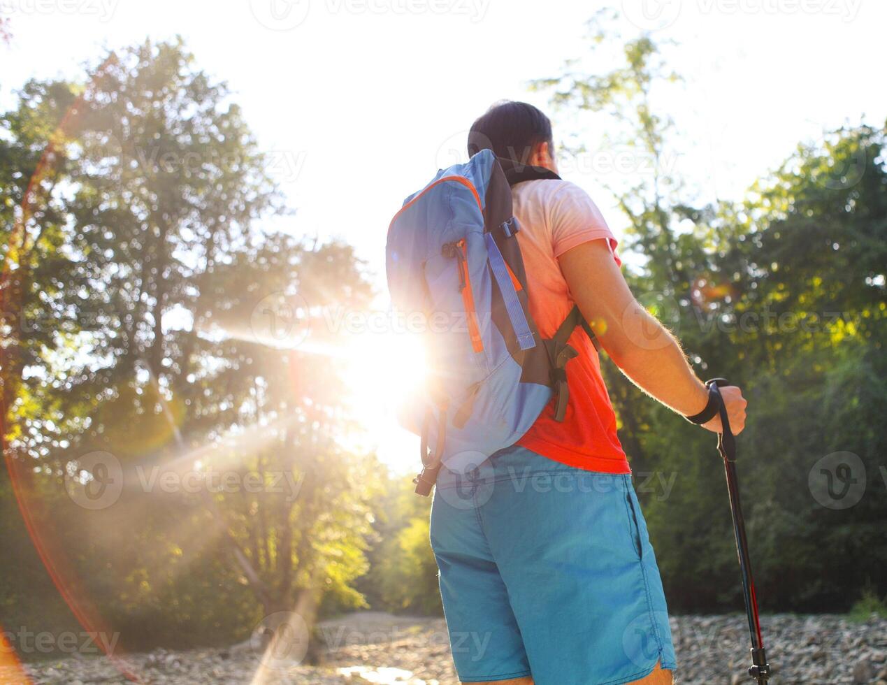 Man hiking with backpac and sticks in mountains in sunset photo