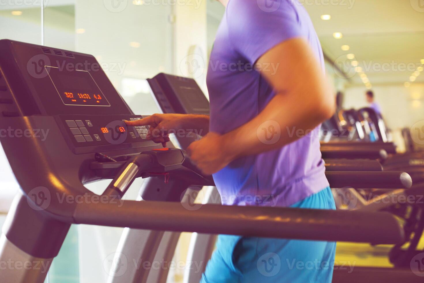 Healthy young man training on a treadmill in a sport center photo