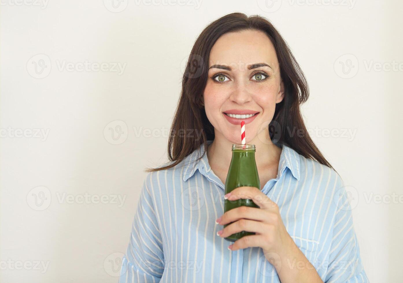 Healthy woman posing with fresh juice bottle of green detox smoothie. Happy beautiful fit girl with fresh juice photo