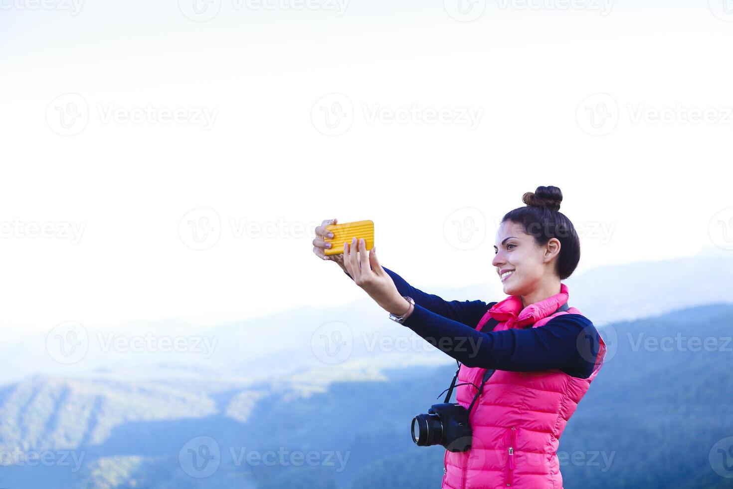 Woman hiker taking photo with smart phone at mountain peak