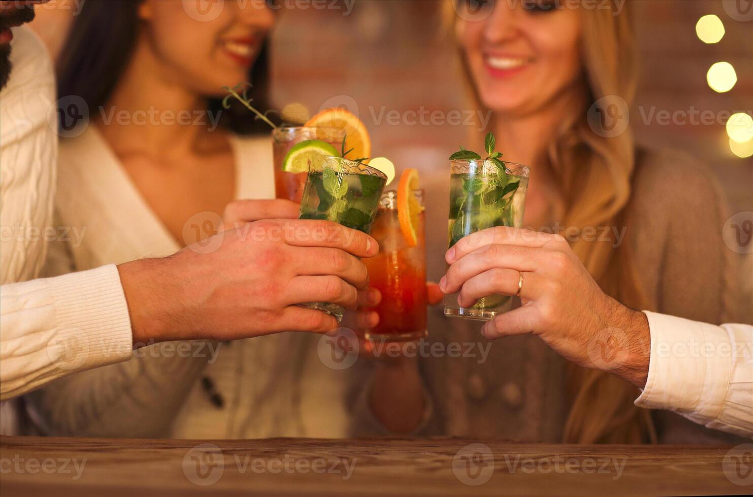 Young men and women drinking cocktail at party photo