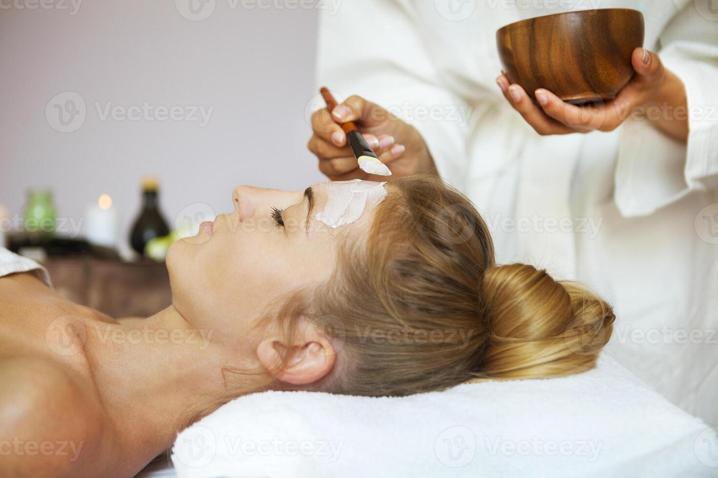 Young beautiful woman in a mask for the face of the therapeutic white mud photo