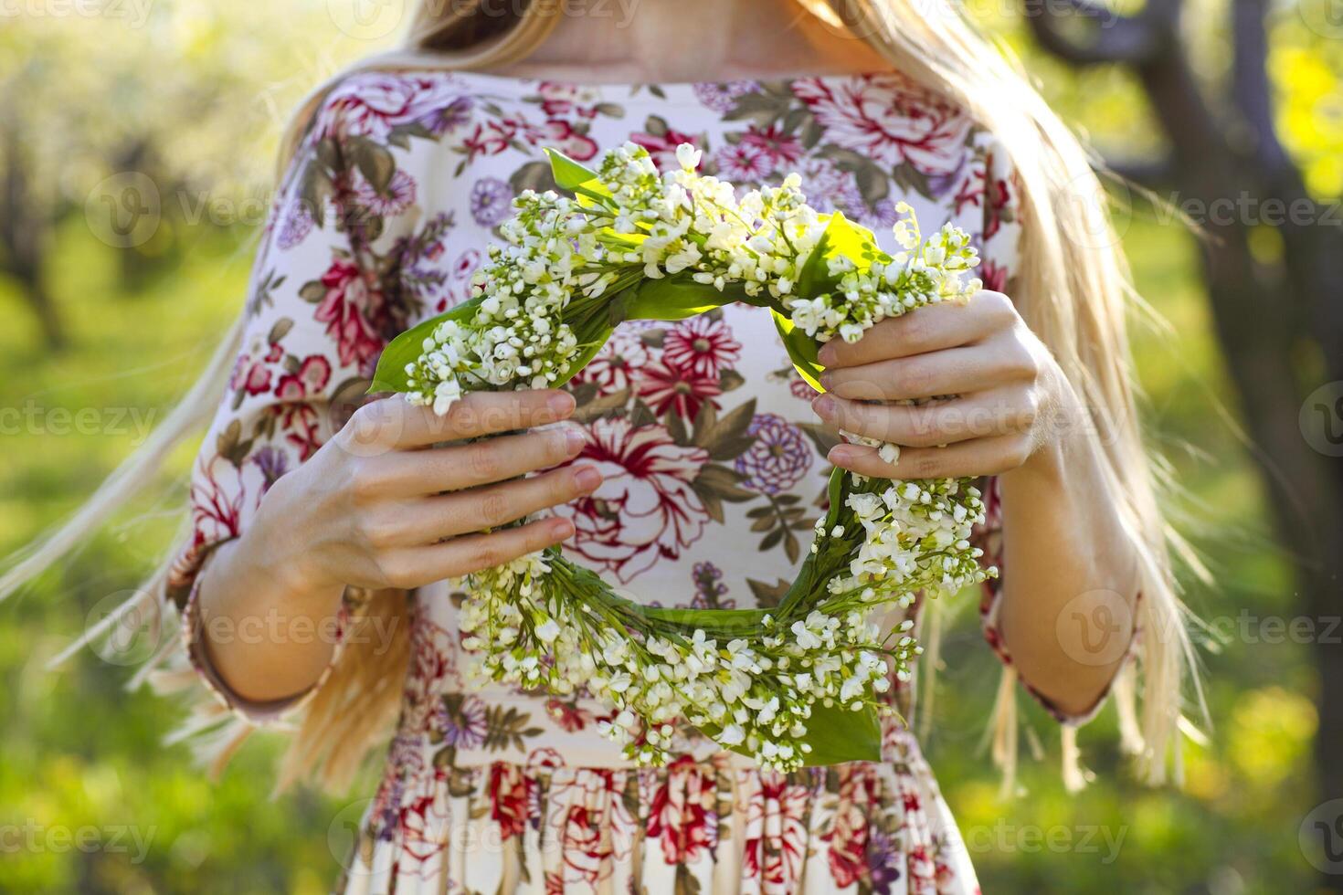 Young woman holding wreath from lily of the valley photo