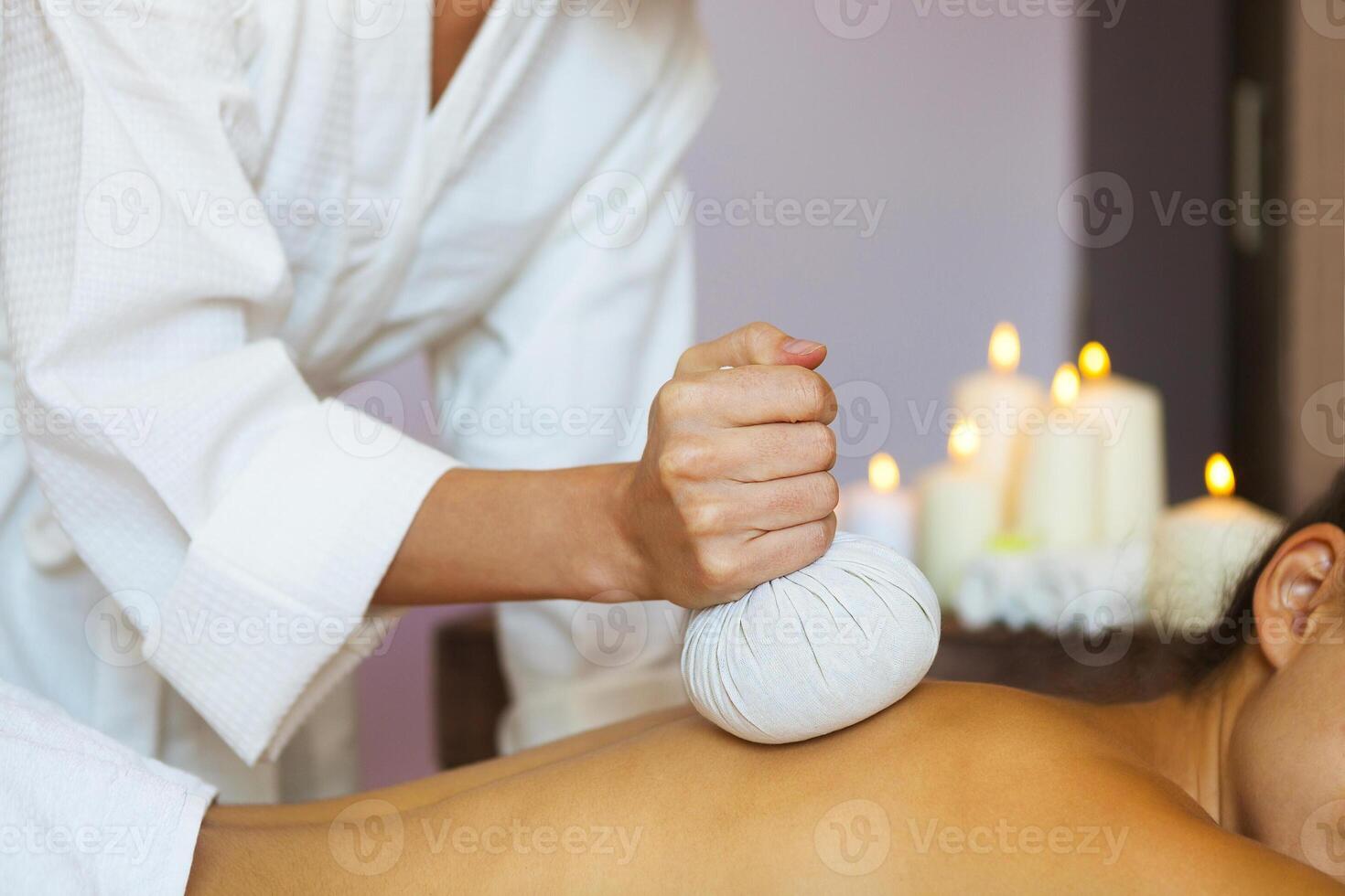 Beautiful young woman having back massage with pouch of rice photo