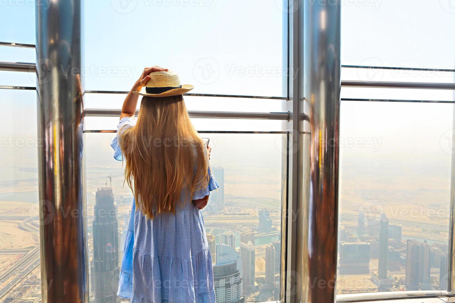 Girl tourist with mobile phone by the window of skyscraper of the Burj Khalifa in Dubai photo