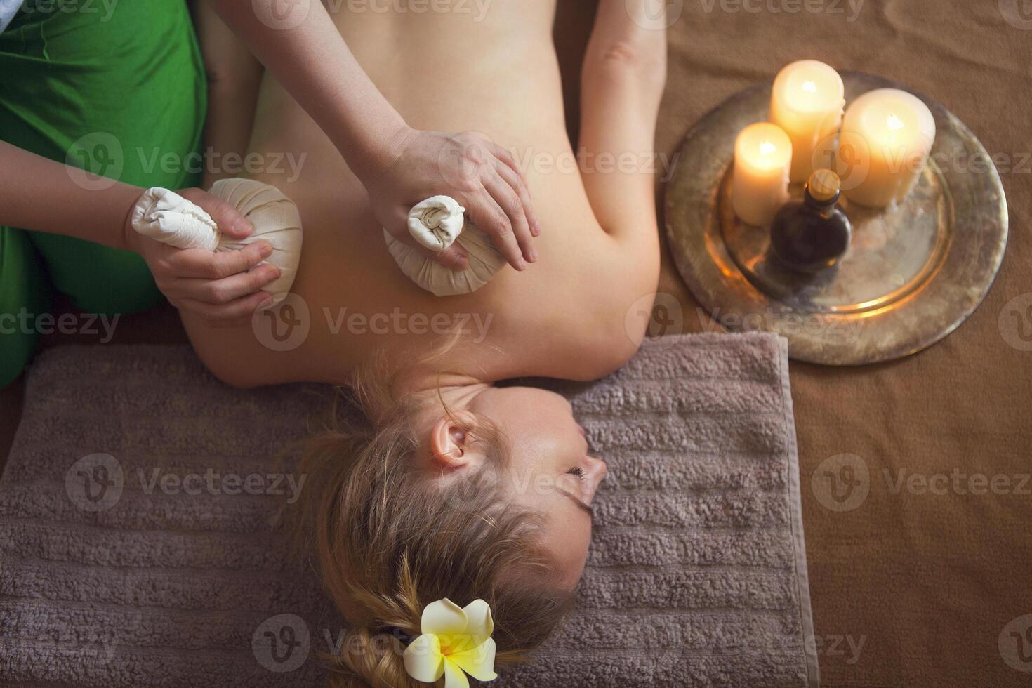 Woman getting thai herbal compress massage in spa photo