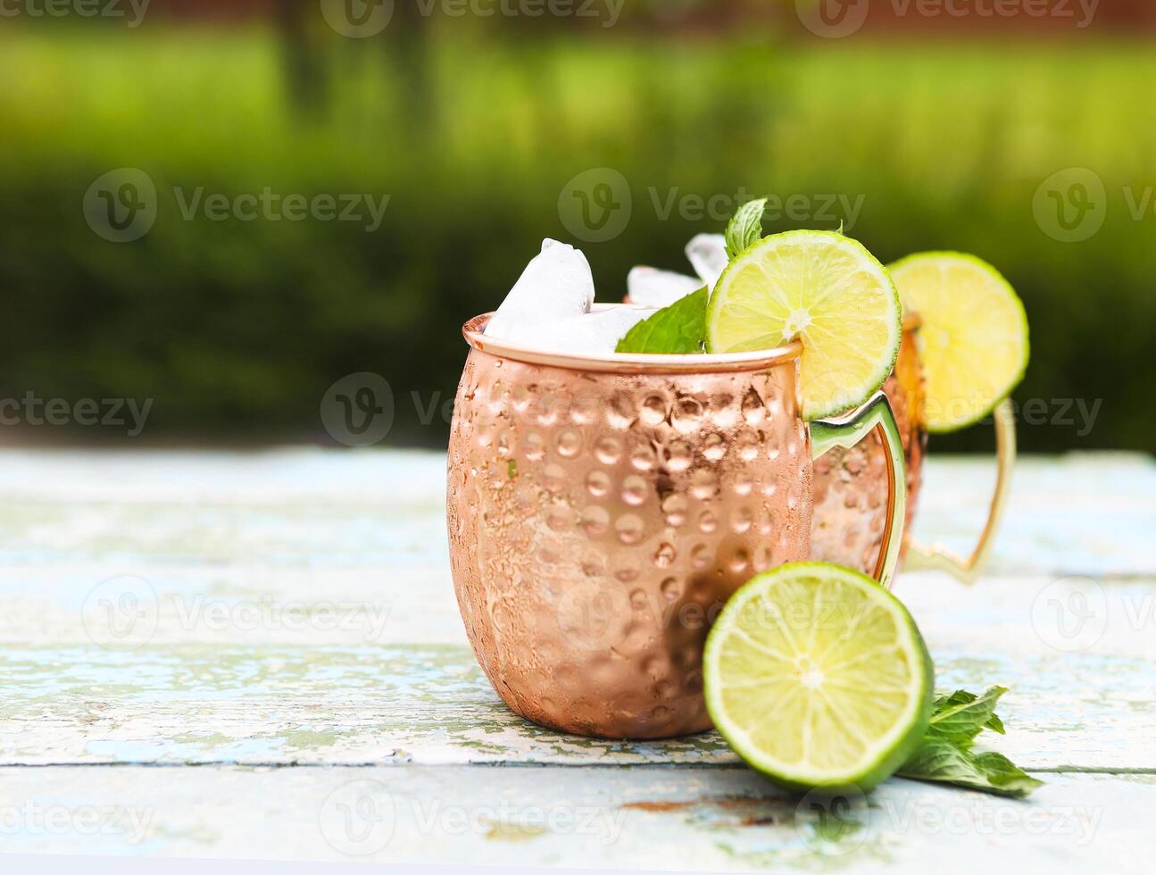 Natural homemade lemonade in cooper mugs on rustic wooden background photo