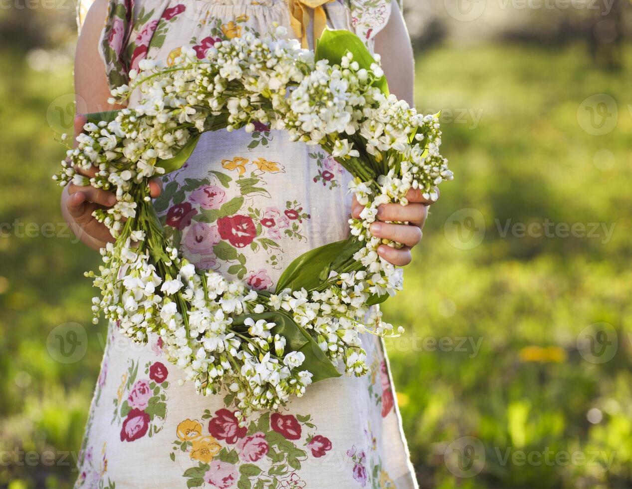 Little girl holding wreath from lily of the valley photo