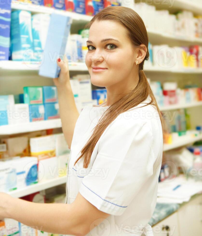 Portrait of young female pharmacist showing medicine box photo