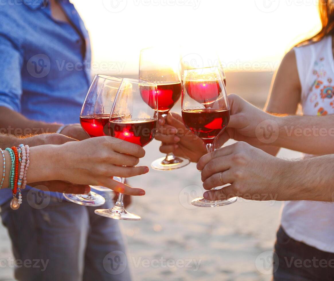 People holding glasses of red wine making a toast at the beach photo