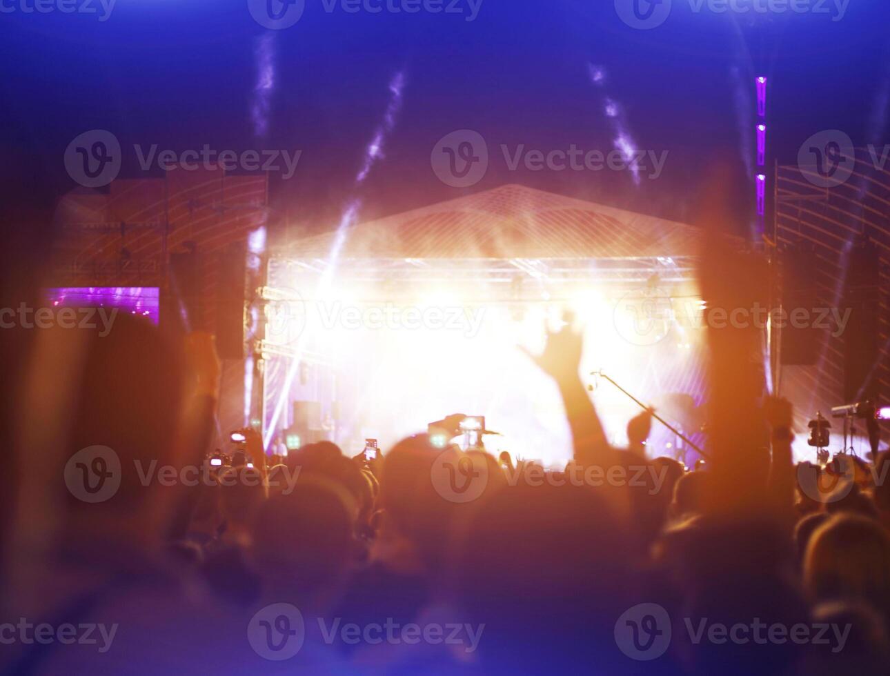 Silhouettes of concert crowd in front of bright stage lights photo