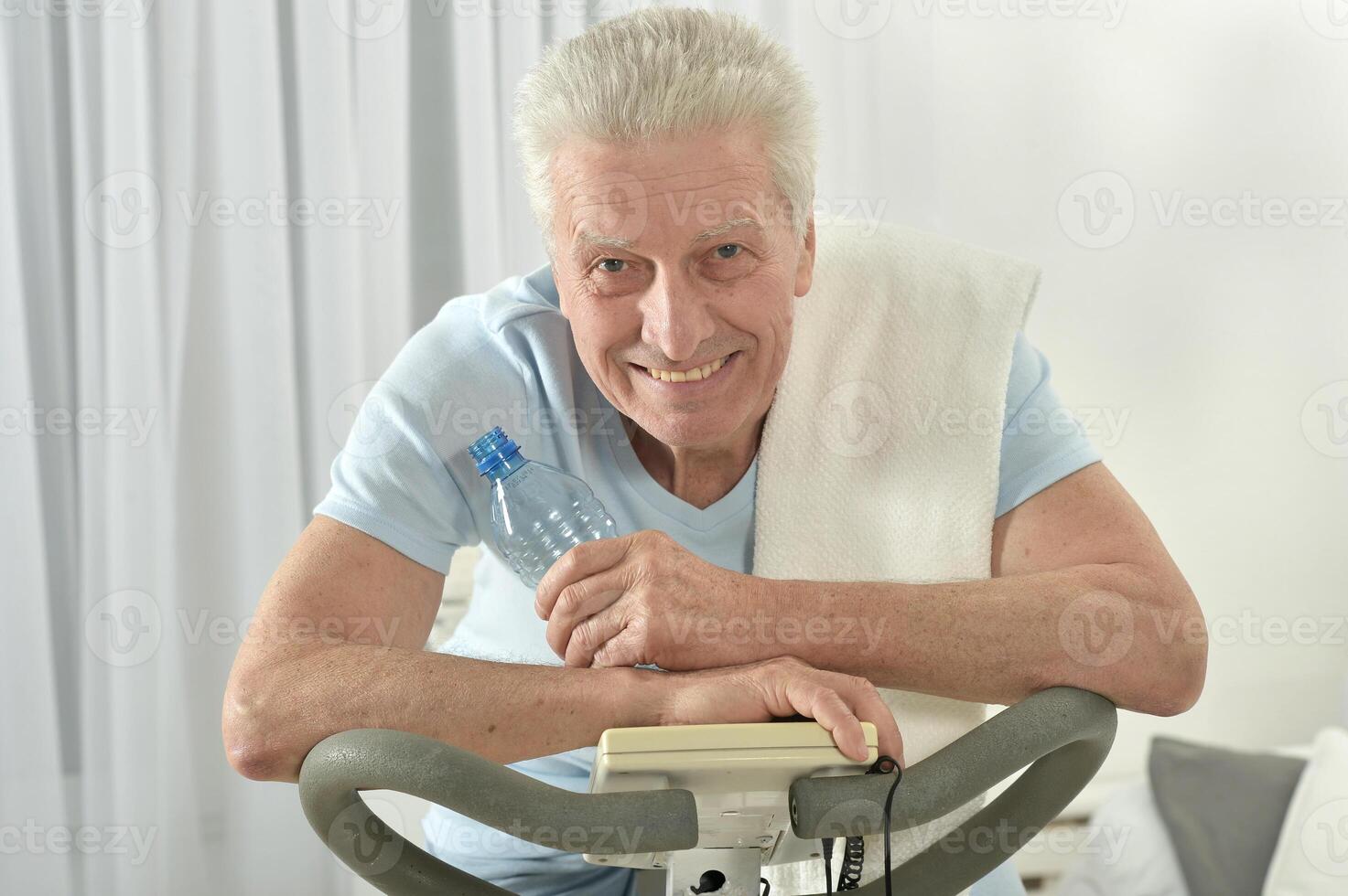 An elderly man is exercising on an exercise bike photo