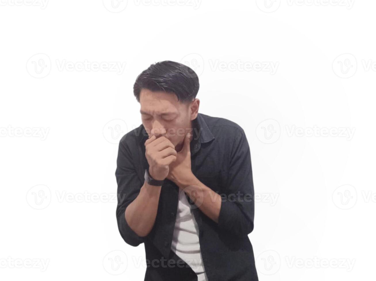 A young man in a black shirt coughs into his hand against a white background. He wears a smartwatch on his right hand photo