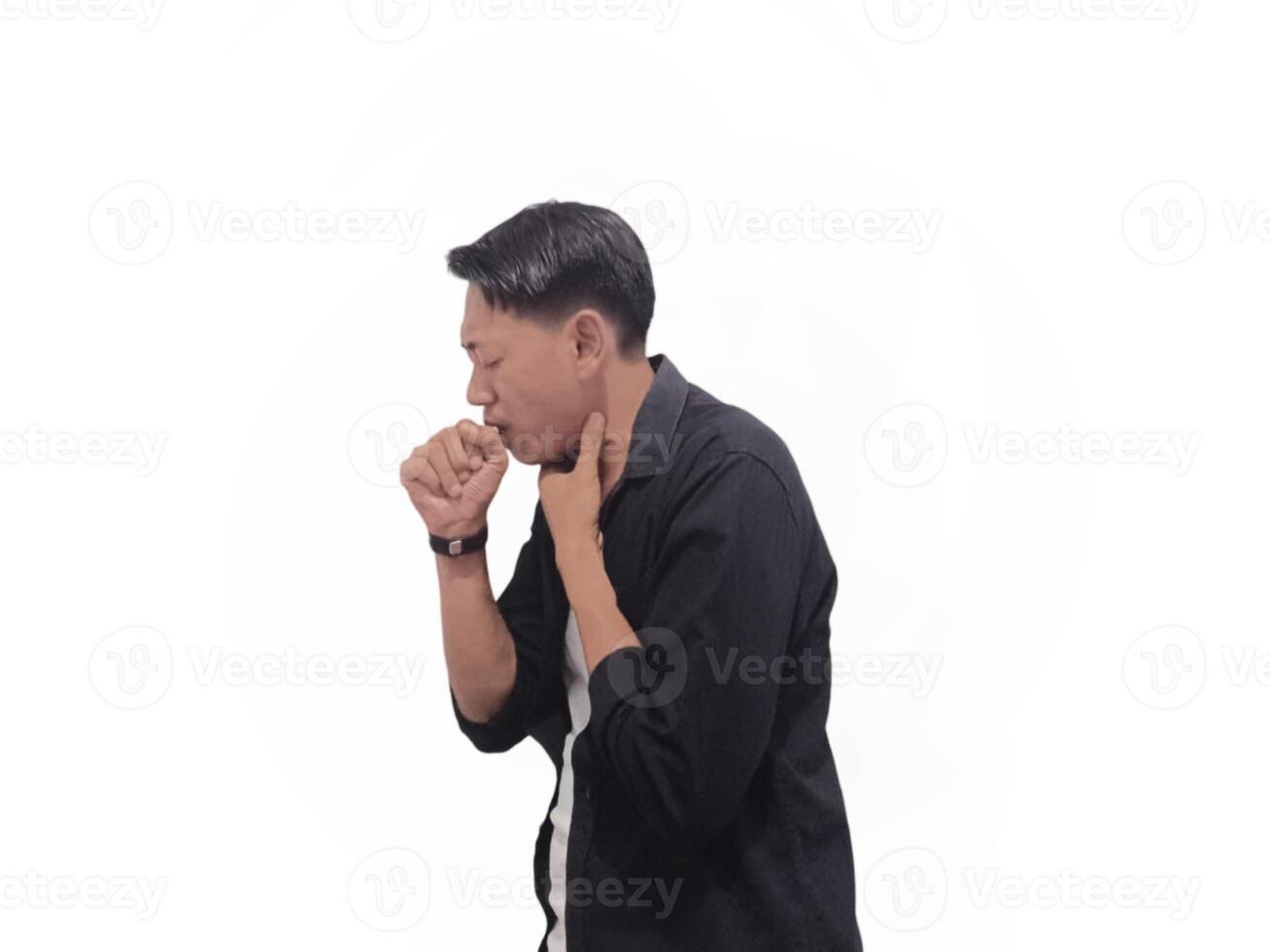 A young man in a black shirt coughs into his hand against a white background. He wears a smartwatch on his right hand photo