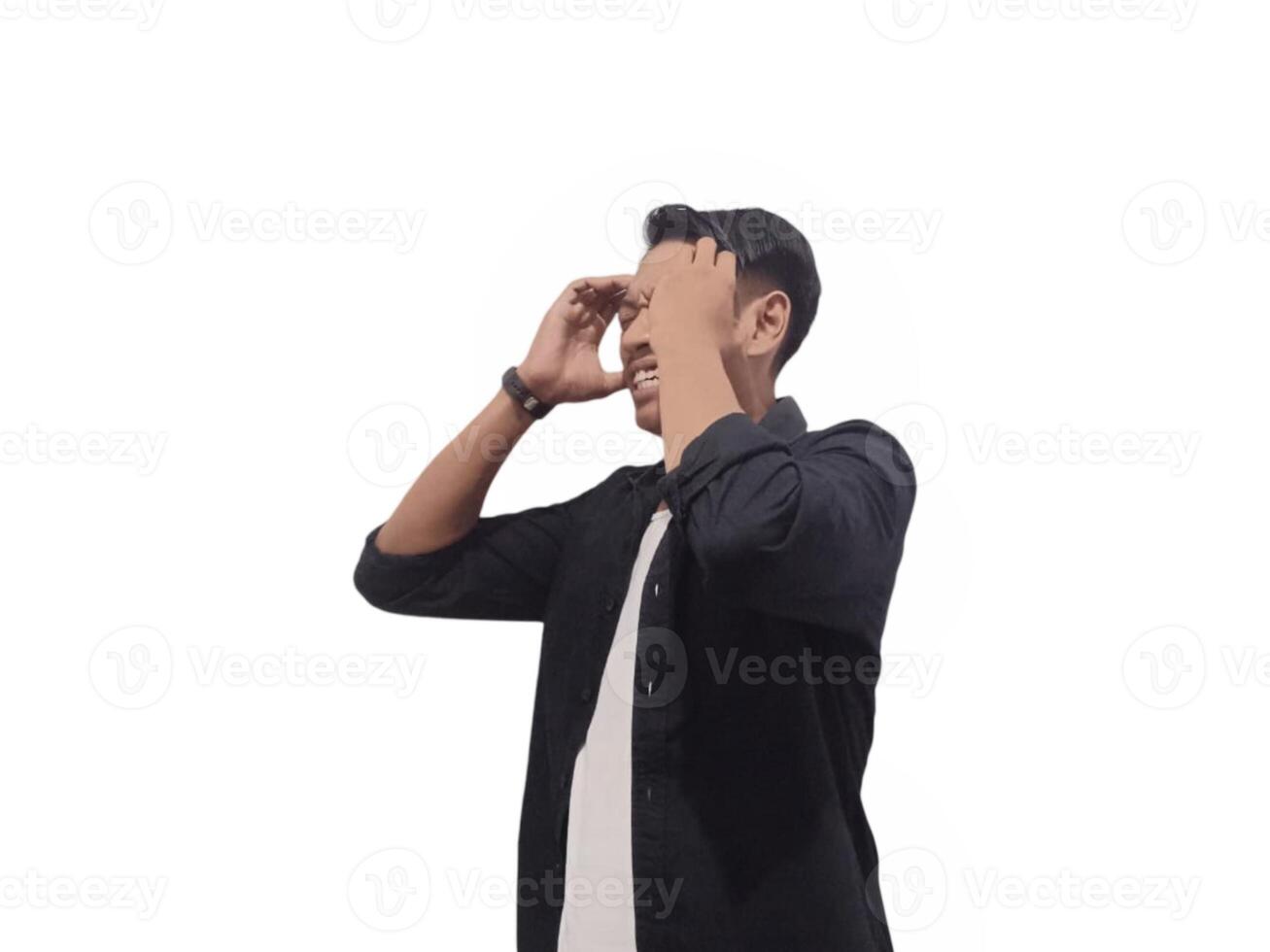 A man in a black shirt holds his head with a pained expression, indicating a headache or discomfort. The plain white background emphasizes his distress and highlights his posture and expression. photo