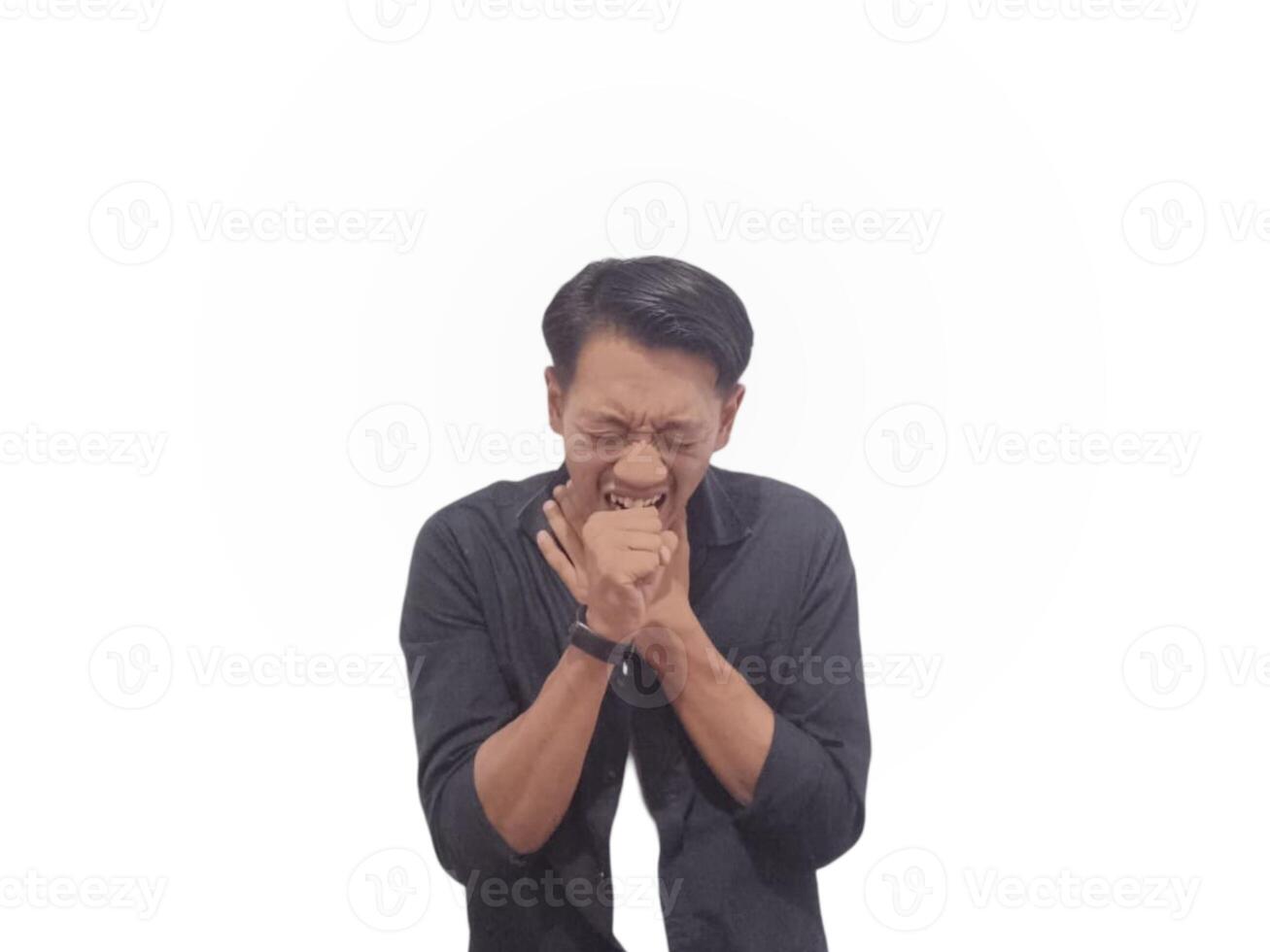 A young man in a black shirt coughs into his hand against a white background. He wears a smartwatch on his right hand photo