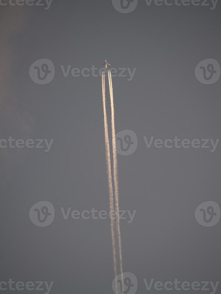 Jet Vapor Trails In Gray Sky Behind Distant Plane photo