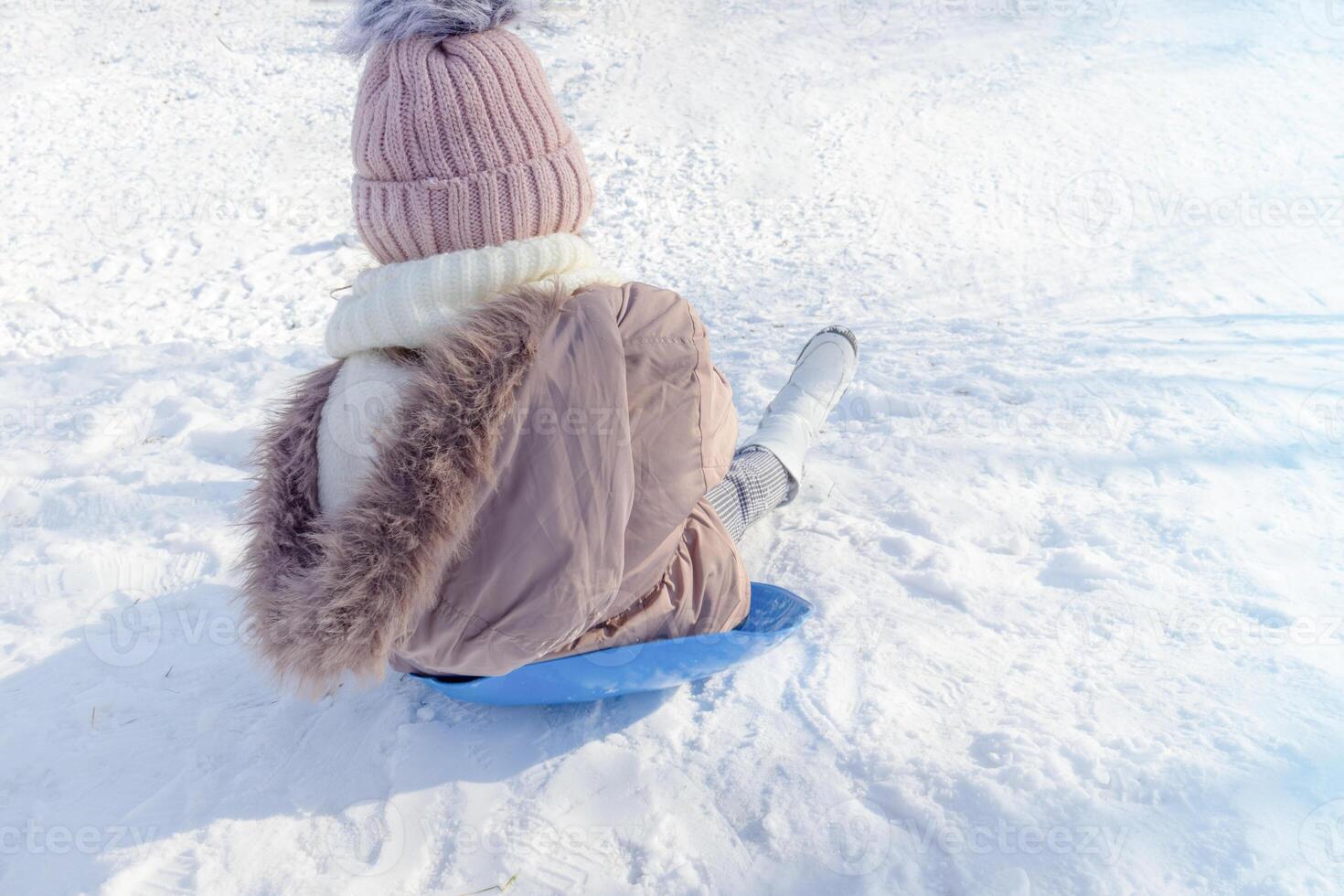Child enjoying a winter day sledding down a snowy hill photo