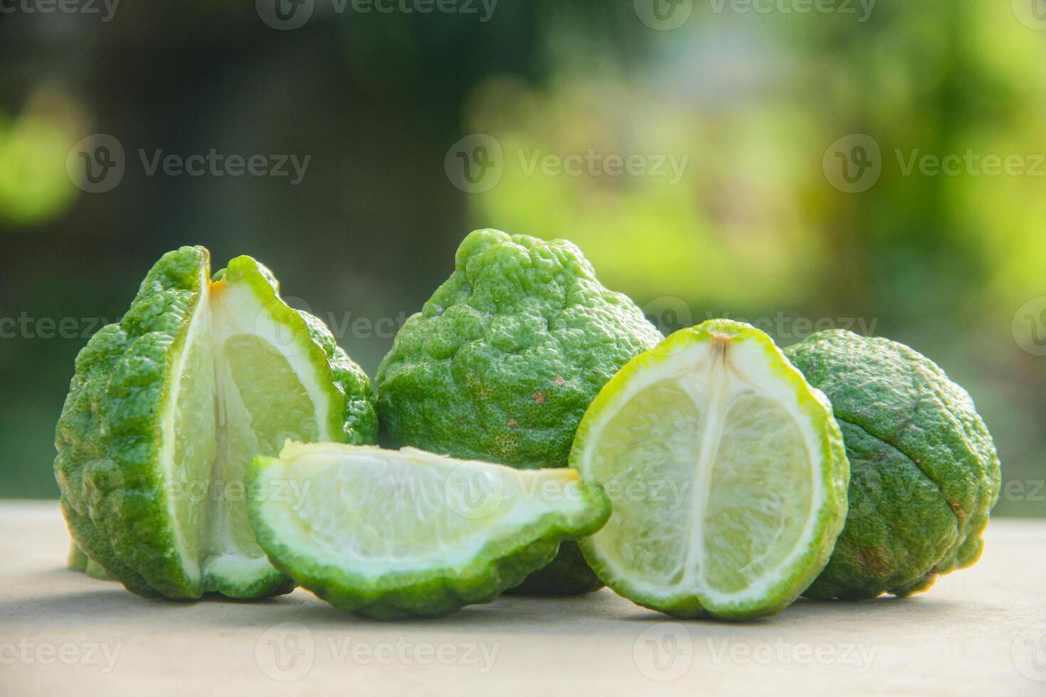 Bergamot fruits or sliced kaffir lime or Citrus hystrix on wooden table and natural green background photo
