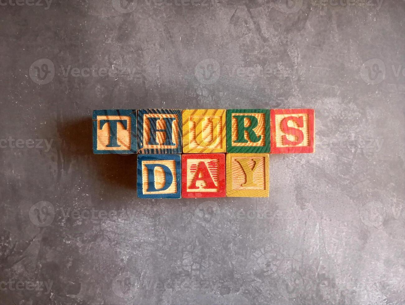 A photo of a wooden block with the words thursday written on it, styled in isolation with space for text.
