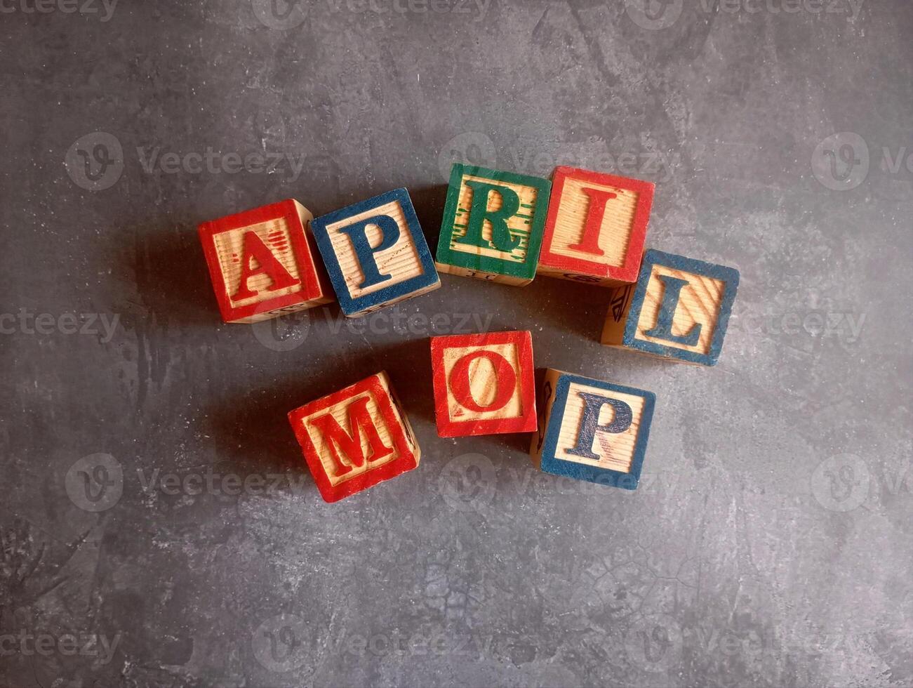 A photo of a wooden block with the words April Mop written on it, styled in isolation with space for text.