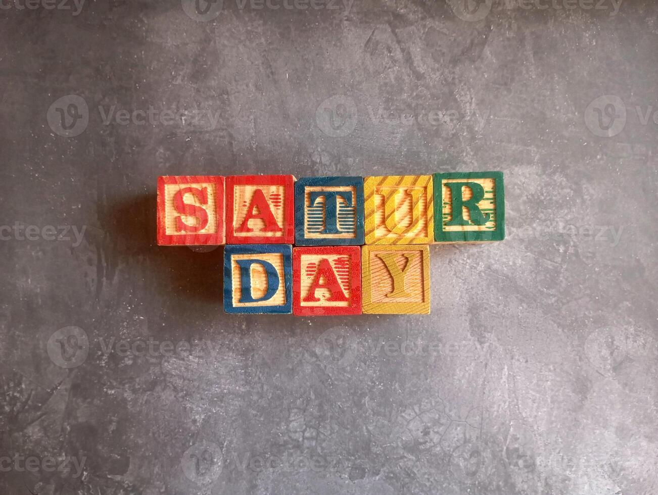 A photo of a wooden block with the words saturday written on it, styled in isolation with space for text.