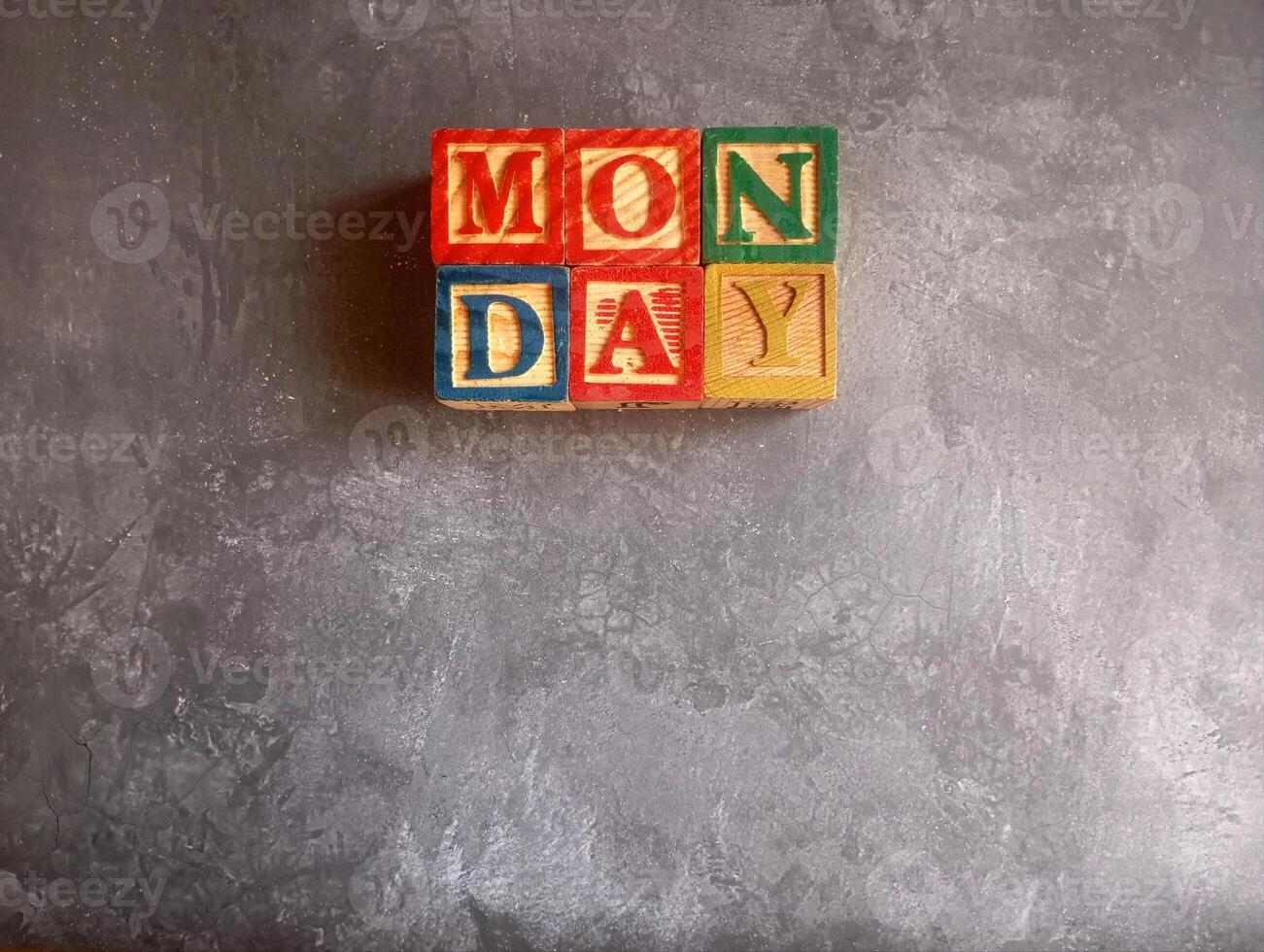 A photo of a wooden block with the words monday written on it, styled in isolation with space for text.