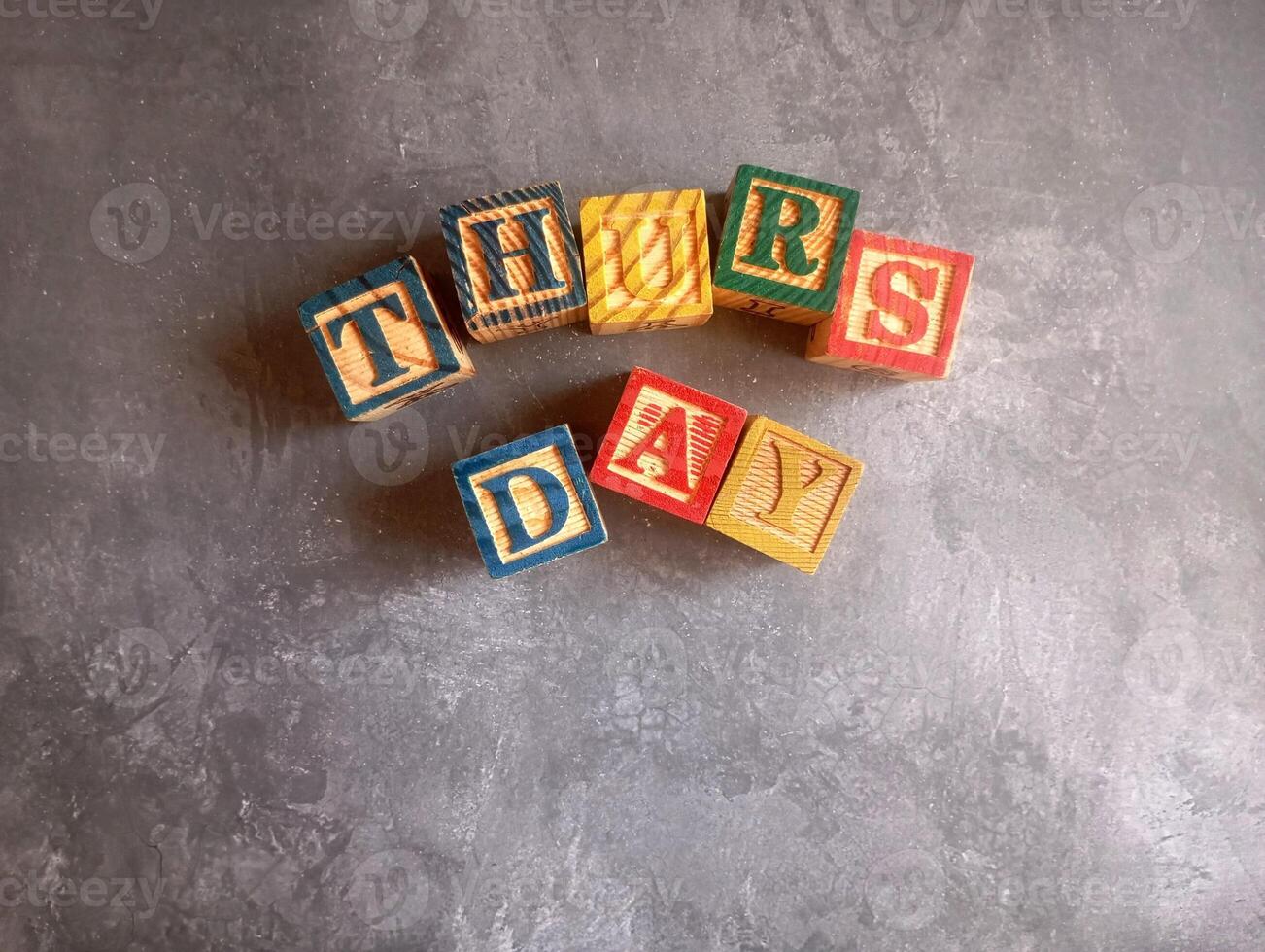 A photo of a wooden block with the words thursday written on it, styled in isolation with space for text.