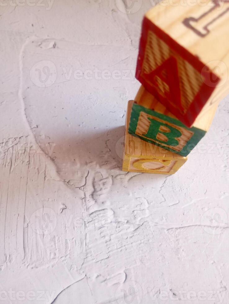 A photo of a wooden block with the words ABC alphabet written on it, styled in isolation with space for text.