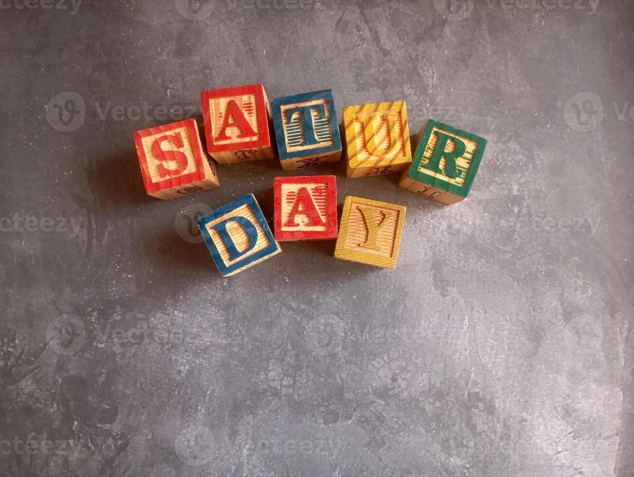 A photo of a wooden block with the words saturday written on it, styled in isolation with space for text.