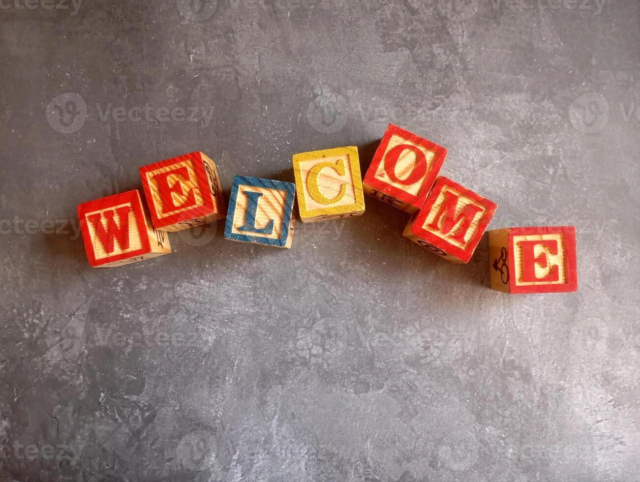 A photo of a wooden block with the words welcome written on it, styled in isolation with space for text.
