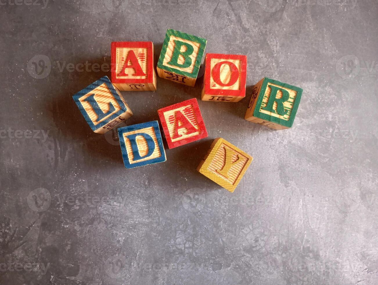 A photo of a wooden block with the words labor day written on it, styled in isolation with space for text.