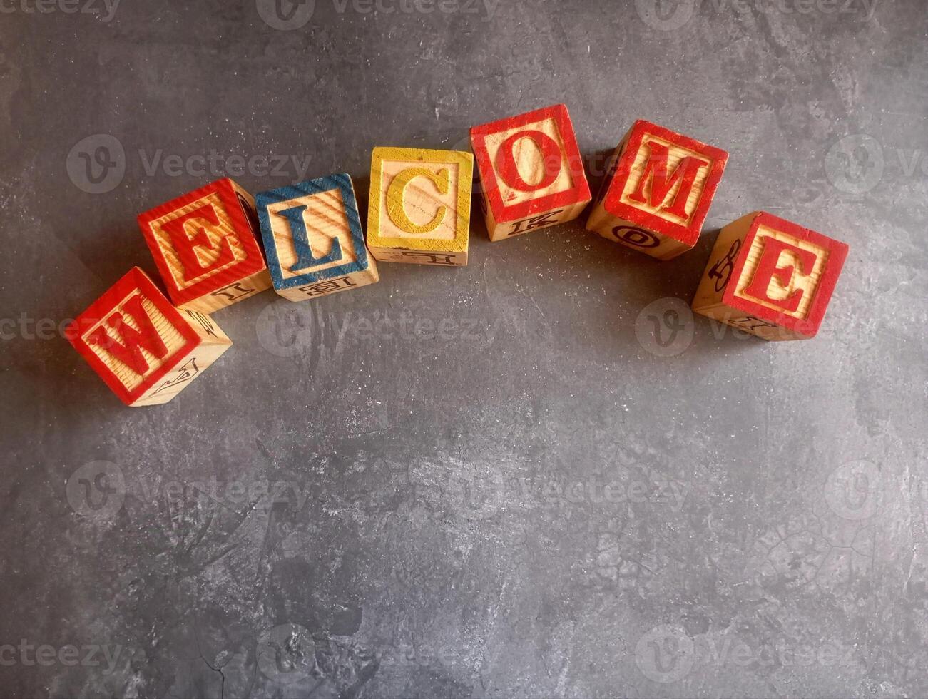 A photo of a wooden block with the words welcome written on it, styled in isolation with space for text.