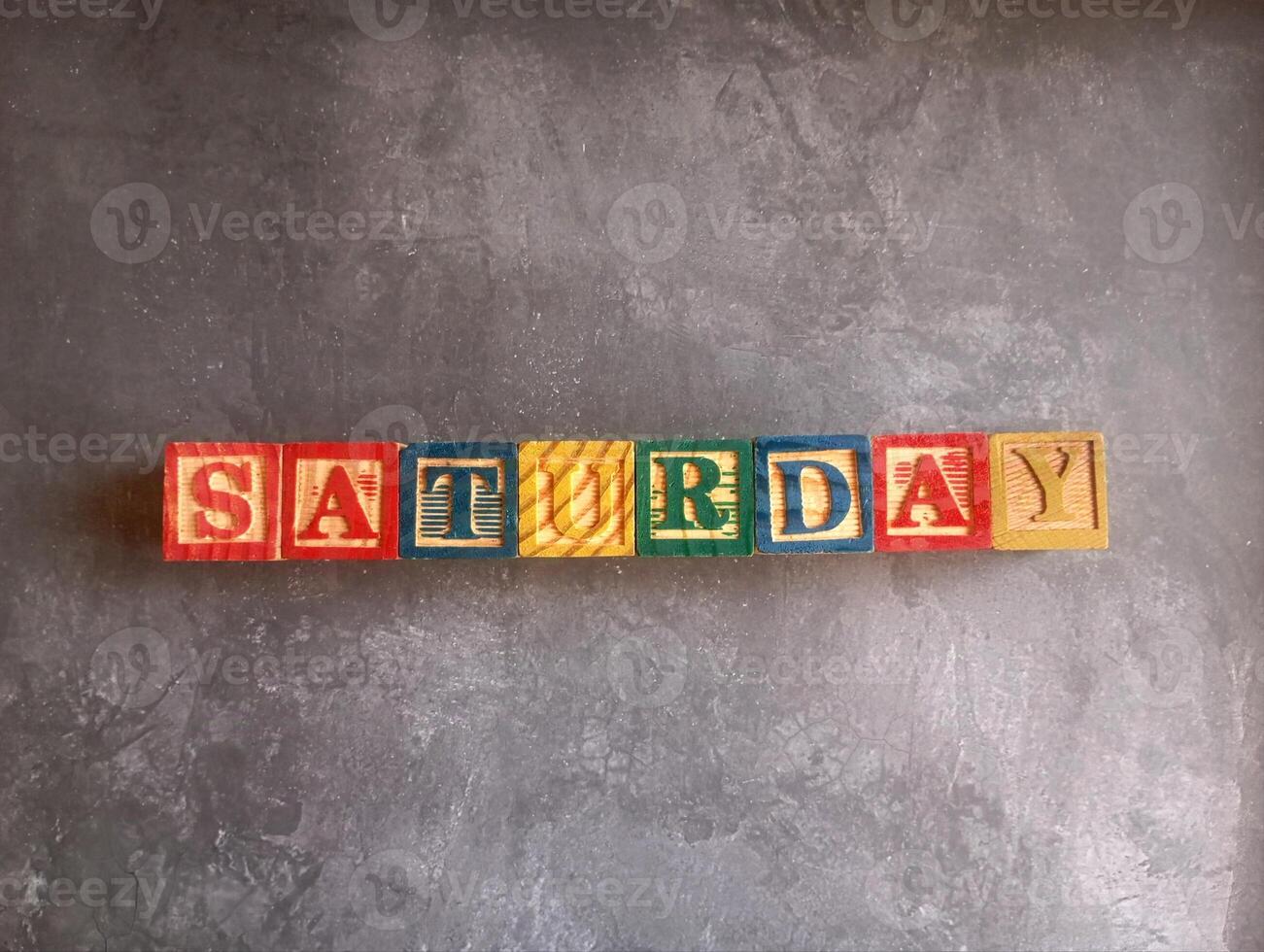 A photo of a wooden block with the words saturday written on it, styled in isolation with space for text.