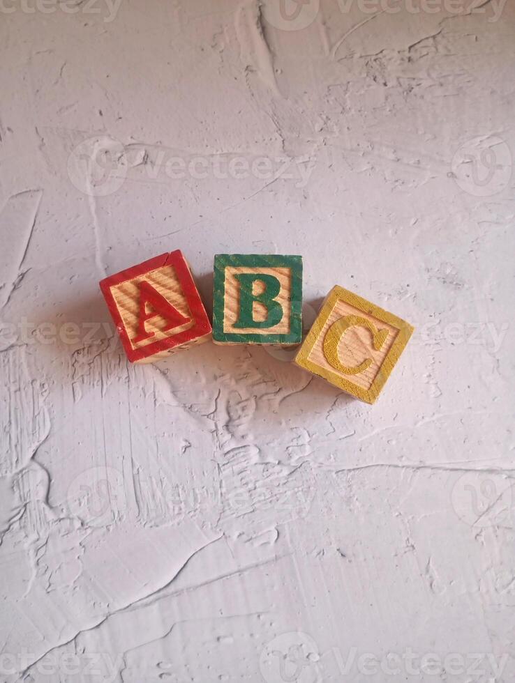 A photo of a wooden block with the words ABC alphabet written on it, styled in isolation with space for text.