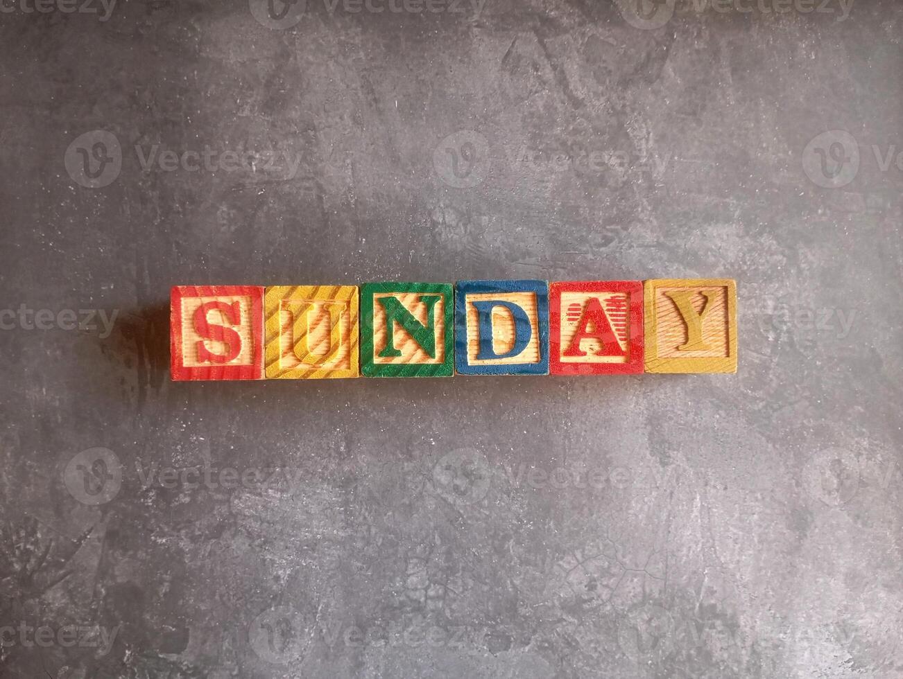 A photo of a wooden block with the words sunday written on it, styled in isolation with space for text.