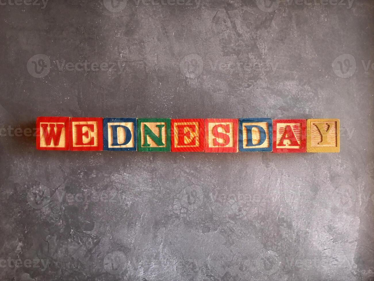 A photo of a wooden block with the words wednesday written on it, styled in isolation with space for text.