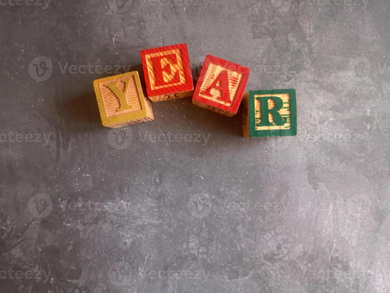 A photo of a wooden block with the words year written on it, styled in isolation with space for text.