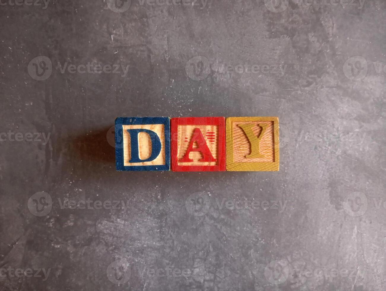 A photo of a wooden block with the words day written on it, styled in isolation with space for text.